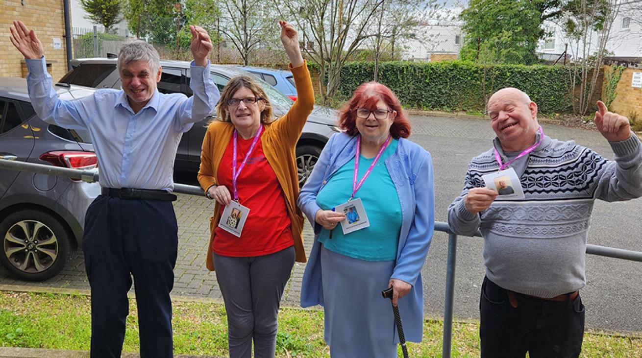 Two men and two women, all residents at Sarnes Court learning disability service, stood outside the service entrance and cheering and smiling for the camera.